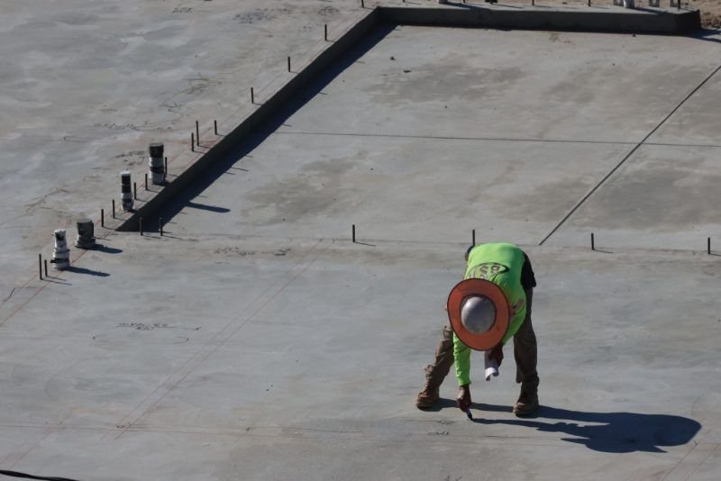 Worker on a large finished concrete slab beside edge forms