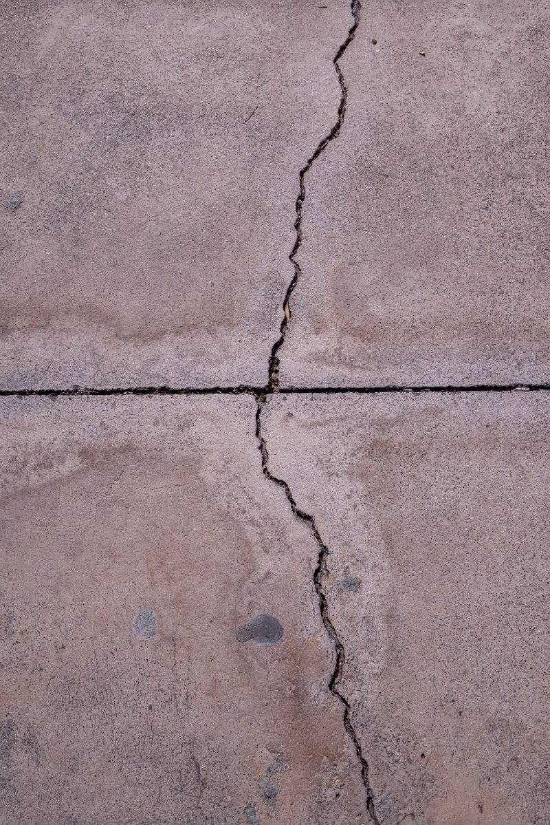 Crack running across a concrete slab and continuing through a control joint